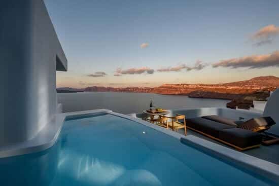 Grande piscine privée extérieure du Neptune Luxury Spa Suites, avec vue sur la caldeira et son pourtour, Akrotiri, Santorin.